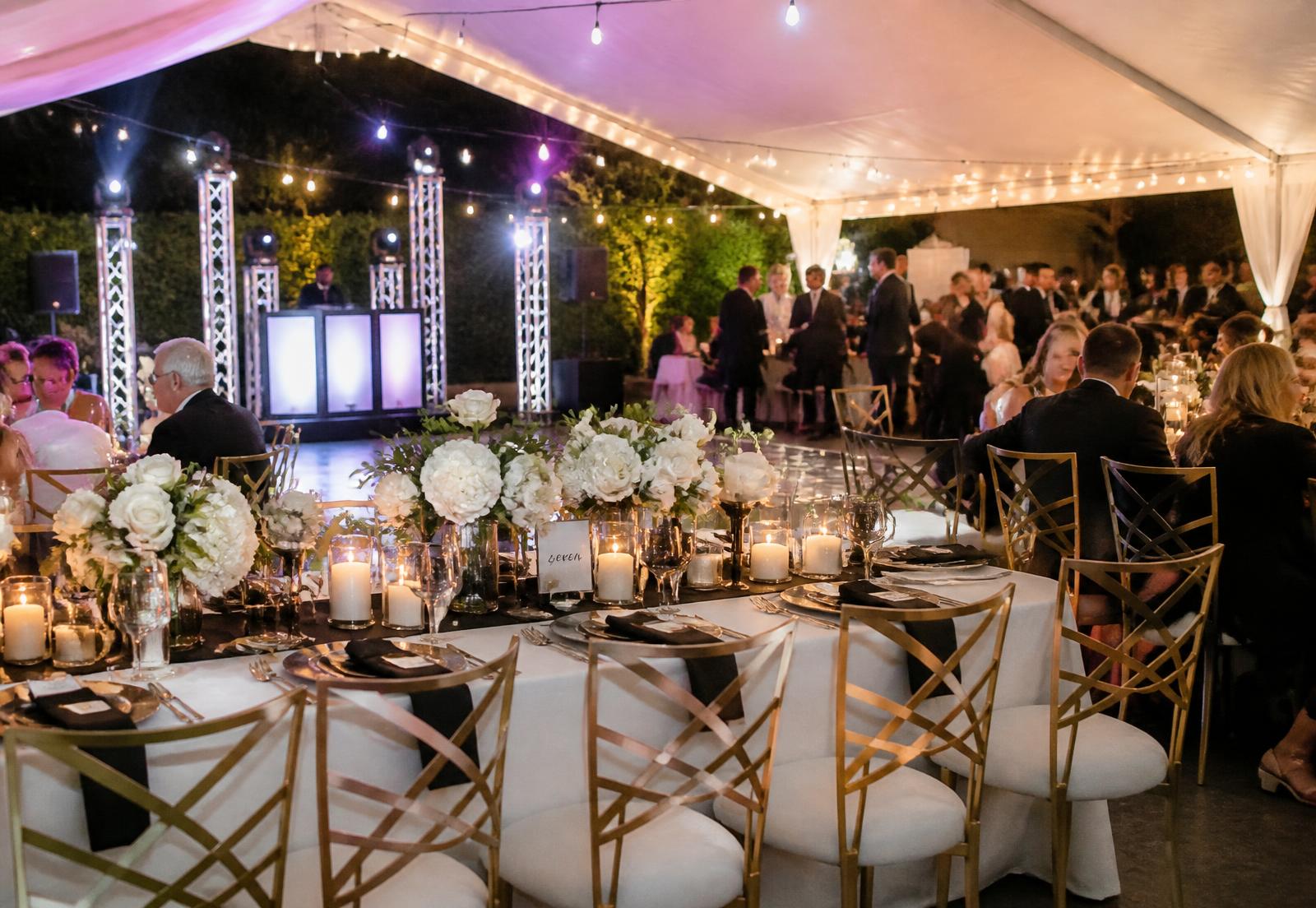 Backyard wedding reception under a tent with candlelit tables